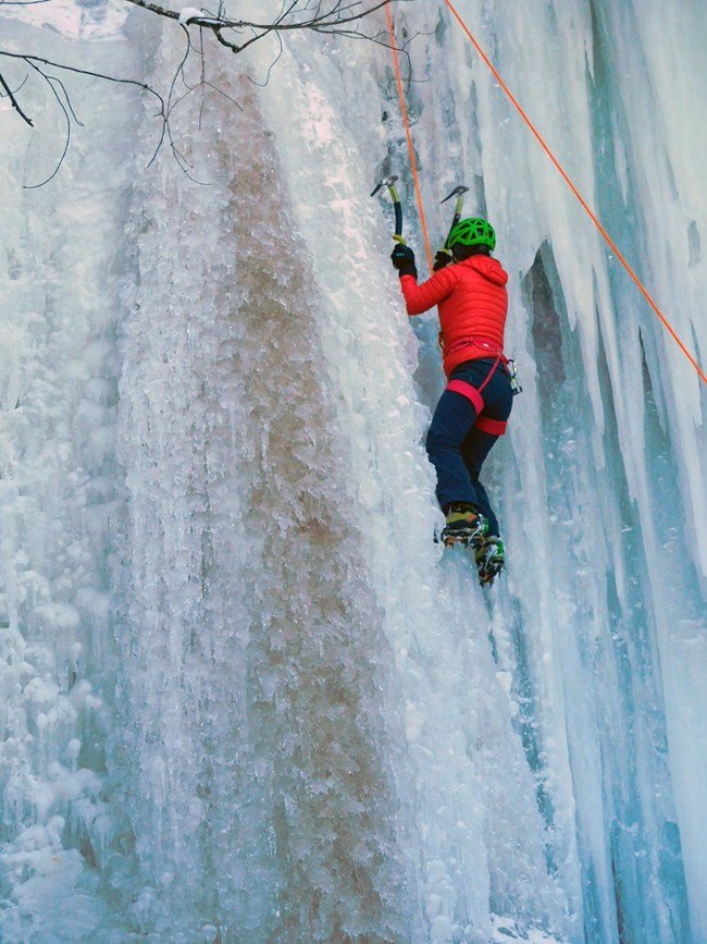 A woman climbs the ice curtains at Sant Point